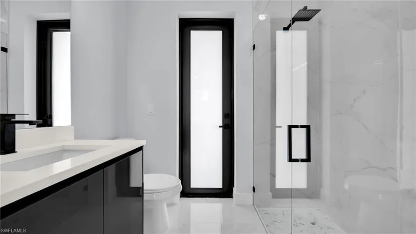 Full bath featuring a marble finish shower, vanity, and light marble finish flooring