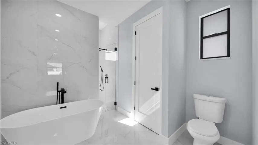 Full bath with marble tiled floors, a marble finish shower, and a freestanding tub