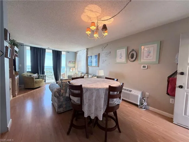 Dining room with a wall of windows, a textured ceiling, wood finished floors, and a chandelier
