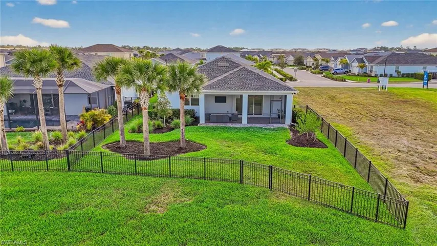 Back of the house with a lanai, and a fenced backyard.
