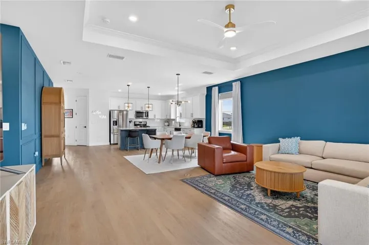 Living room with a ceiling fan, crown molding, a tray ceiling, and recessed lighting