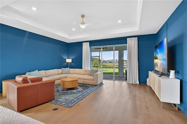 Living room with a ceiling fan, ornamental molding, a tray ceiling, and recessed lighting