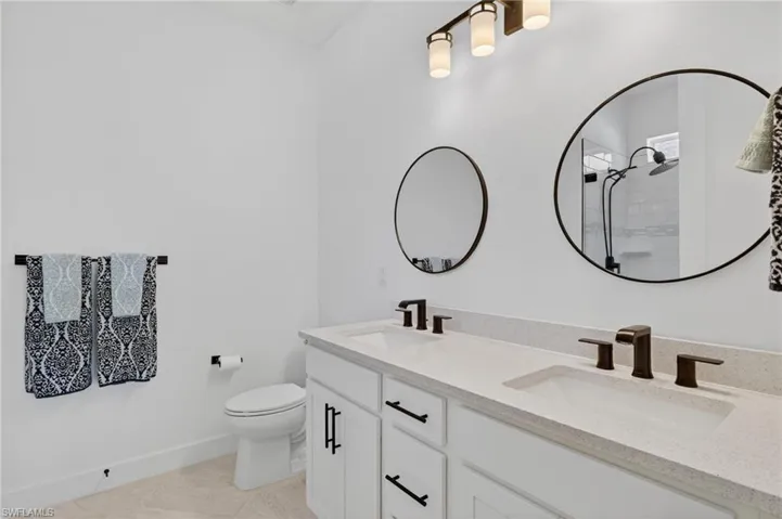 Bathroom featuring double vanity, light tile patterned floors, and a tile shower