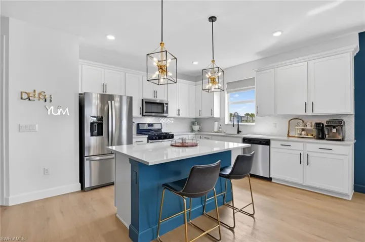 Kitchen with stainless steel appliances, white cabinets, a breakfast bar area, a center island