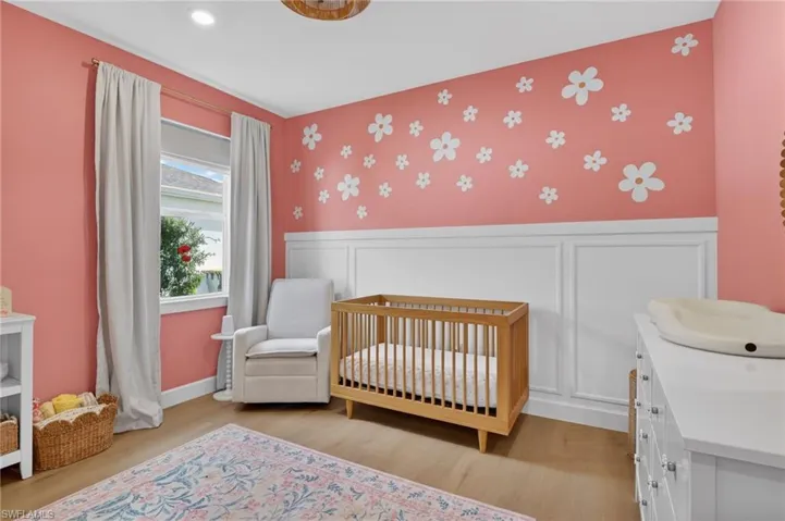 Bedroom featuring a nursery area, wallpapered walls, a wainscoted wall, and a decorative wall