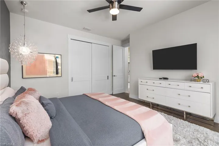 Bedroom featuring wood finished floors, a closet, a chandelier, a ceiling fan, and baseboards