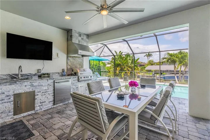 View of patio with ceiling fan, a sink, a lanai, an outdoor pool, and outdoor dining area