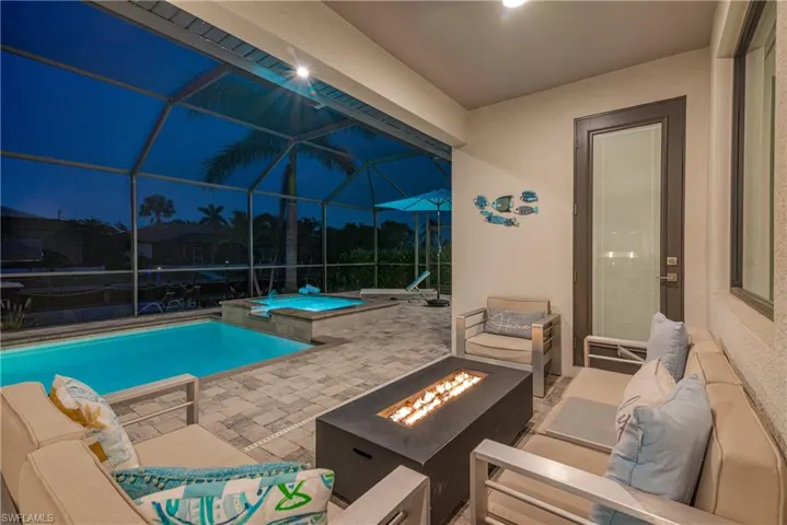 View of pool featuring a patio, an outdoor living space with a fire pit, glass enclosure, and a pool with connected hot tub