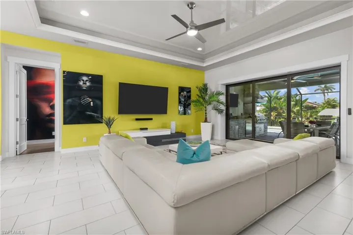 Living room featuring a ceiling fan, a tray ceiling, baseboards, recessed lighting, and light tile patterned floors