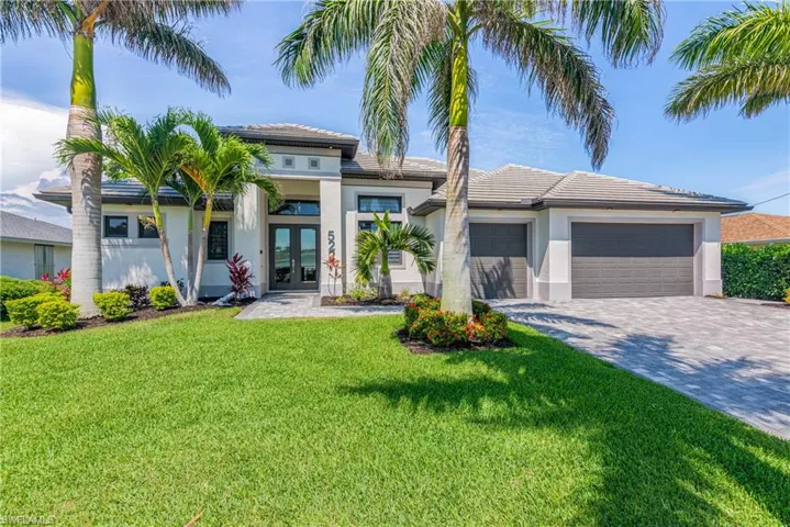Prairie-style home with french doors, stucco siding, decorative driveway, a garage, and a front lawn