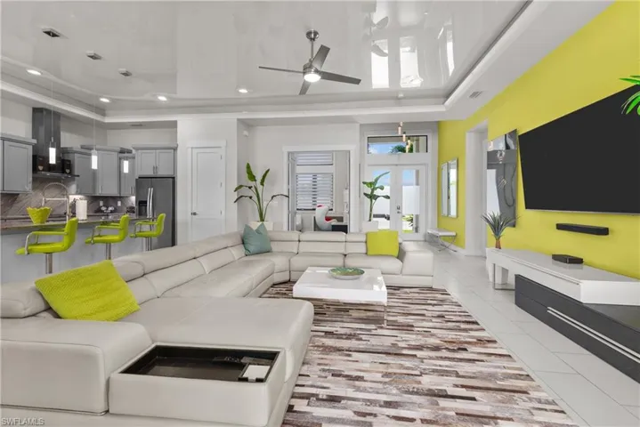 Living room featuring a tray ceiling, ceiling fan, recessed lighting, light tile patterned flooring, and french doors