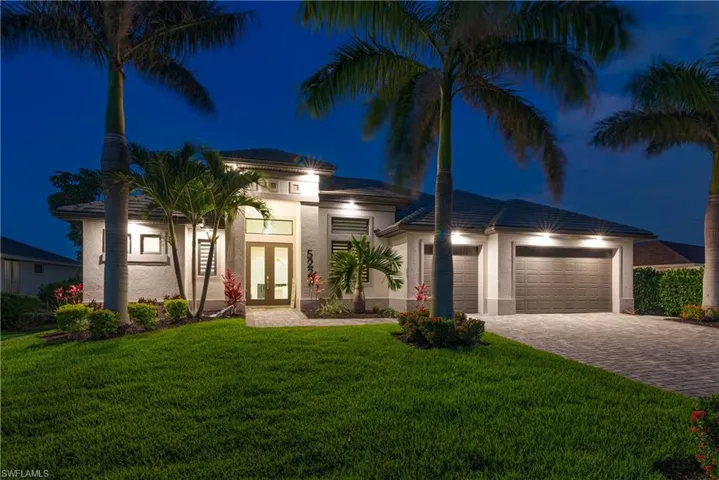 View of front of house featuring french doors, decorative driveway, an attached garage, stucco siding, and a lawn