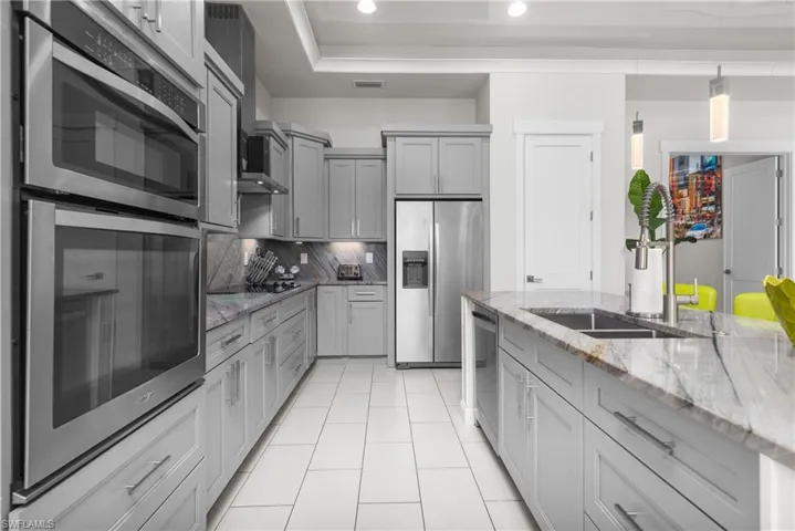 Kitchen with appliances with stainless steel finishes, recessed lighting, light tile patterned floors, gray cabinetry, and a sink
