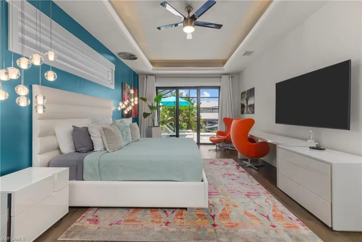 Bedroom with a raised ceiling, wood finished floors, and a ceiling fan