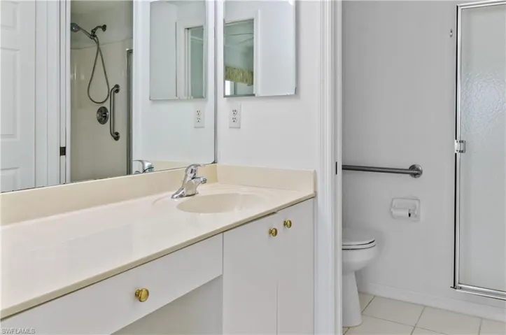 Bathroom featuring vanity, toilet, an enclosed shower, and tile patterned flooring