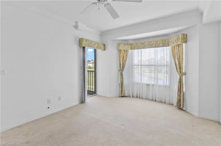 Carpeted empty room featuring ceiling fan and ornamental molding