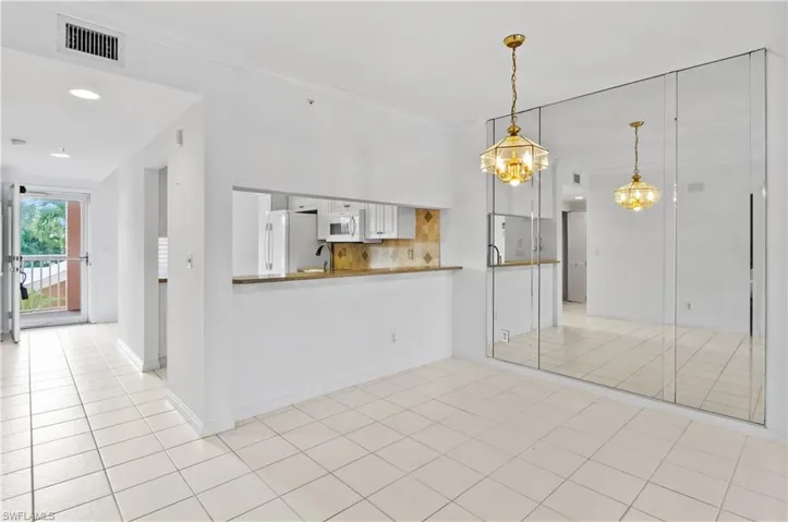 Kitchen with white appliances, a notable chandelier, light tile patterned floors, crown molding, and kitchen peninsula