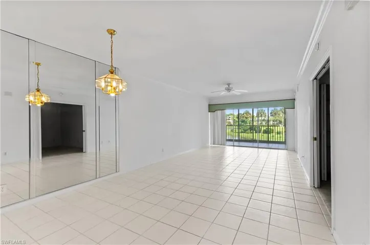 Unfurnished room with crown molding, ceiling fan with notable chandelier, and light tile patterned flooring