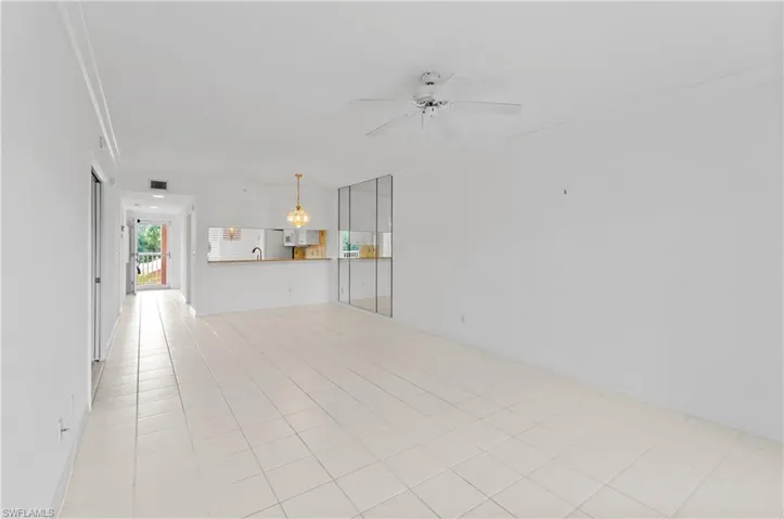 Unfurnished living room with ceiling fan, light tile patterned floors, sink, and ornamental molding