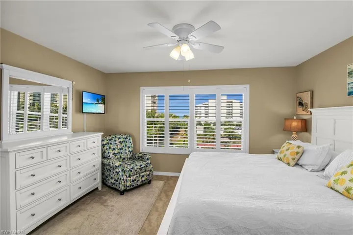 Bedroom with light colored carpet, baseboards, and a ceiling fan
