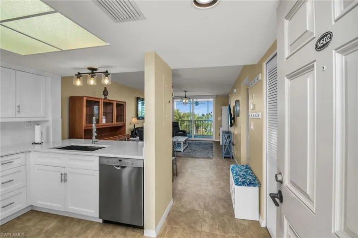 Kitchen featuring stainless steel dishwasher, a sink, light countertops, white cabinetry, and light tile patterned floors