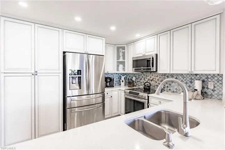Kitchen featuring stainless steel appliances, white cabinetry, tasteful backsplash, and sink