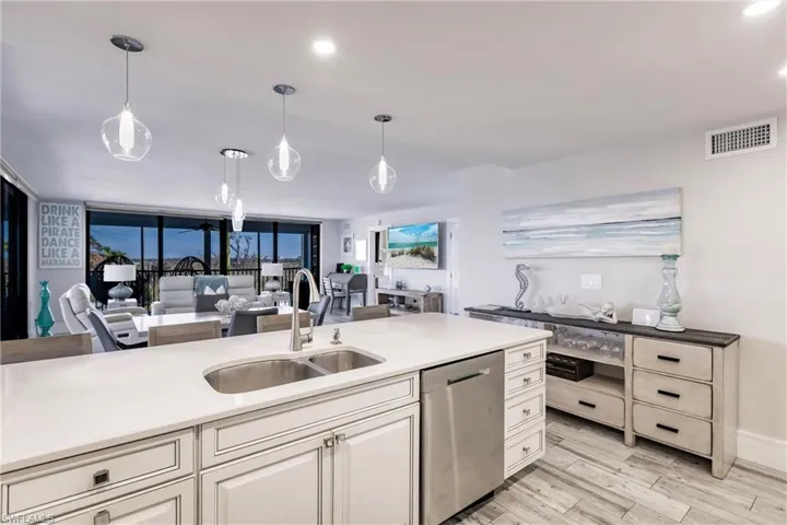 Kitchen featuring pendant lighting, stainless steel dishwasher, floor to ceiling windows, and sink