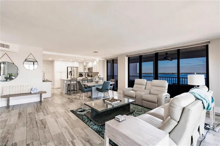 Living room featuring ceiling fan, a water view, a wall of windows, and light hardwood / wood-style flooring