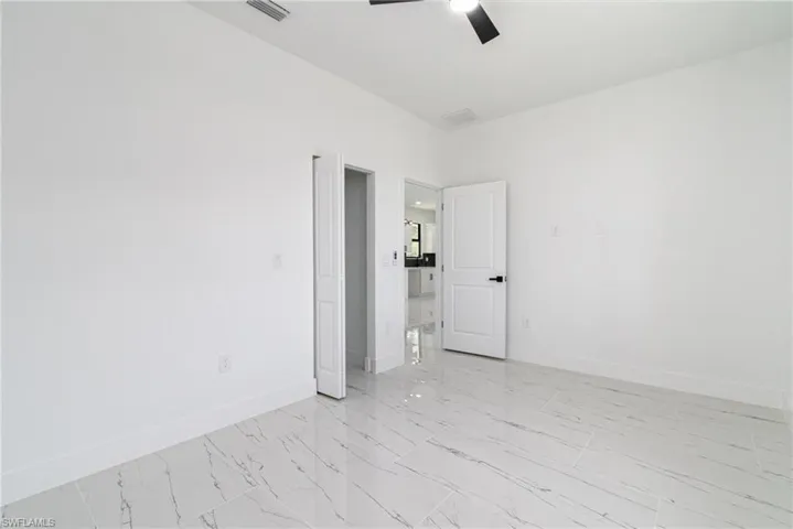 Empty room featuring marble finish floor, ceiling fan, baseboards, and visible vents