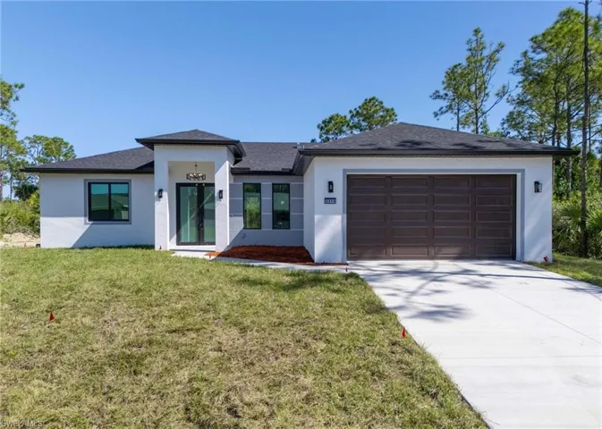 Prairie-style home featuring roof with shingles, stucco siding, driveway, a front yard, and a garage