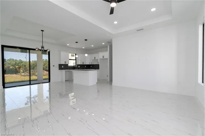 Unfurnished living room with visible vents, a raised ceiling, recessed lighting, ceiling fan with notable chandelier, and marble finish floor
