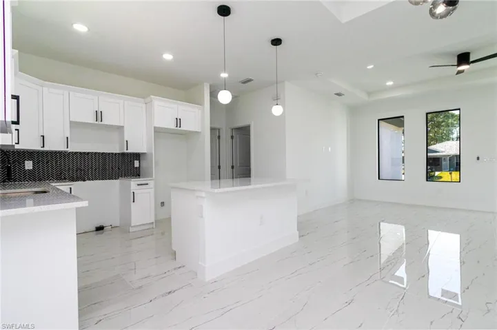 Kitchen with open floor plan, recessed lighting, decorative backsplash, and a kitchen island