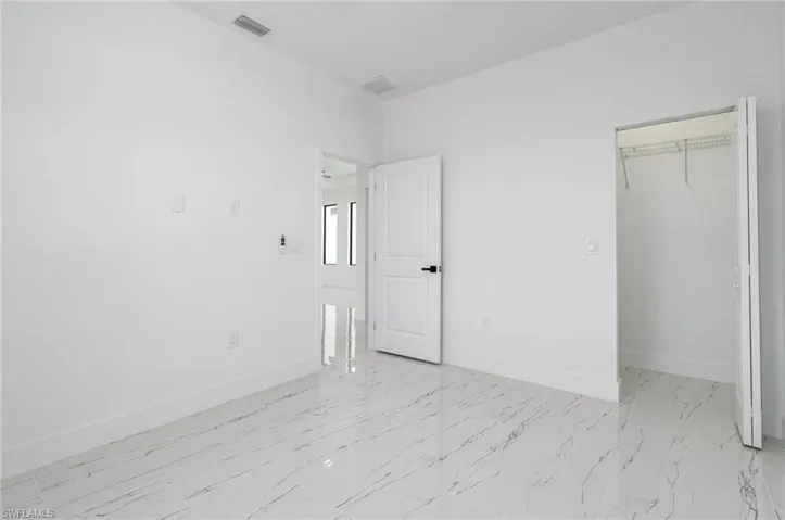 Unfurnished bedroom featuring a closet, baseboards, a spacious closet, visible vents, and marble finish floor