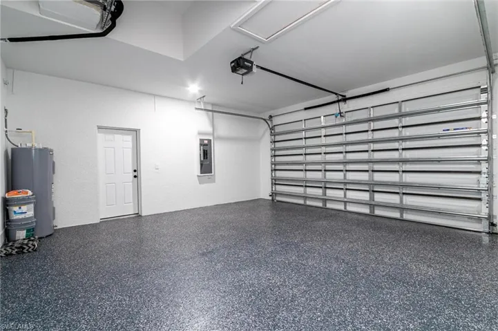 Garage featuring electric panel, water heater, and a garage door opener