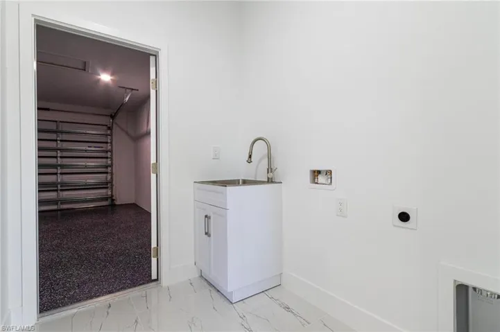 Washroom featuring hookup for an electric dryer, hookup for a washing machine, cabinet space, marble finish floor, and a sink