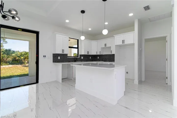 Kitchen featuring tasteful backsplash, a healthy amount of sunlight, visible vents, and a kitchen island