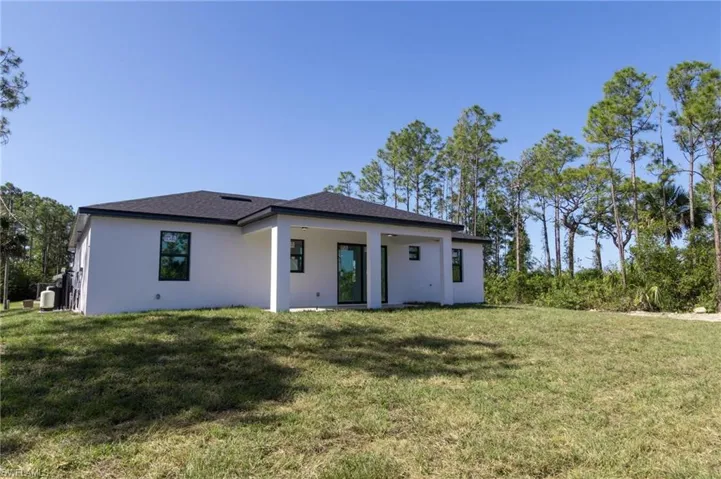 Back of house with a yard and stucco siding