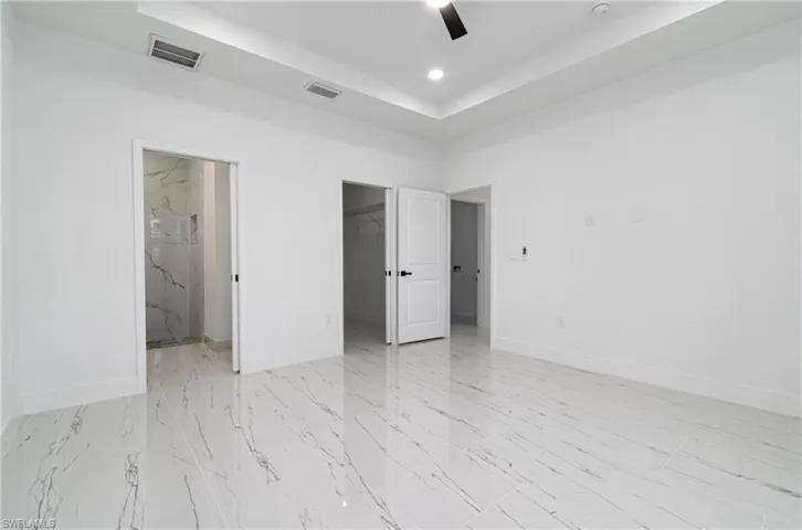 Unfurnished bedroom featuring visible vents, baseboards, a raised ceiling, and marble finish floor