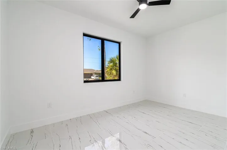 Unfurnished room with marble finish floor, baseboards, and ceiling fan