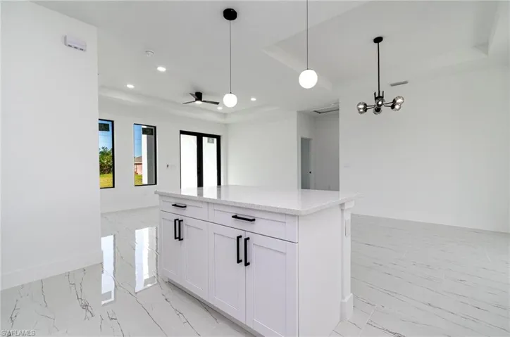 Kitchen with baseboards, recessed lighting, open floor plan, a raised ceiling, and marble finish floor