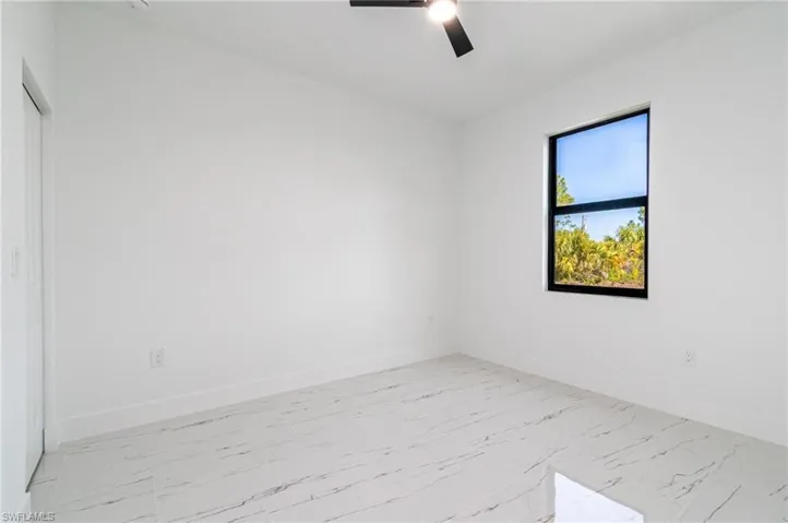 Spare room featuring ceiling fan, marble finish floor, and baseboards