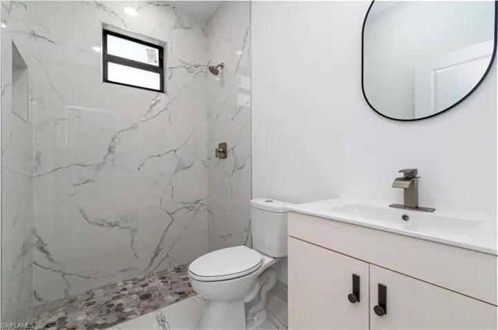 Full bathroom featuring vanity, marble finish floor, toilet, and a marble finish shower