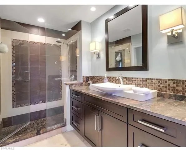Full bath with a shower stall, vanity, and decorative backsplash