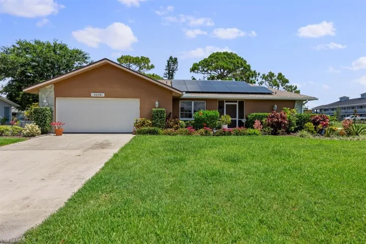 Ranch-style home featuring stucco siding, a front yard, a garage, and driveway
