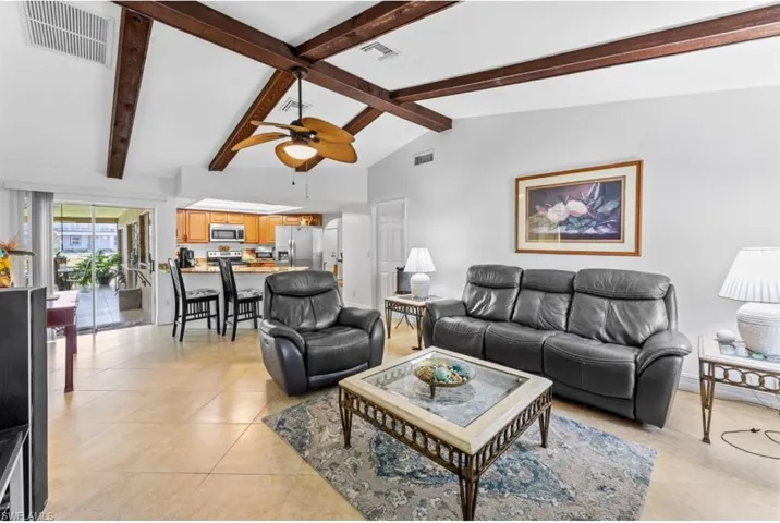 Living room featuring beam ceiling, high vaulted ceiling, light tile patterned flooring, and a ceiling fan