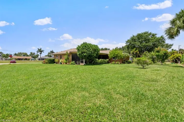 View of grassy yard with a sunroom