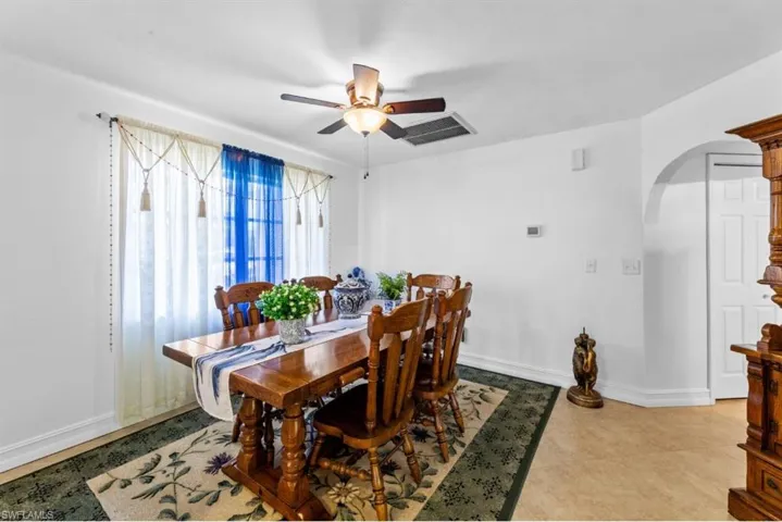 Dining area featuring arched walkways, ceiling fan, and light tile patterned floors
