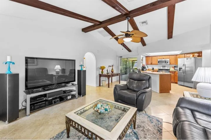 Living area with high vaulted ceiling, arched walkways, a ceiling fan, beam ceiling, and light tile patterned floors