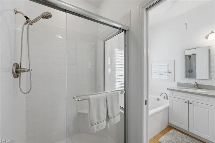 The serene primary suite offers private lanai access and a beautifully appointed ensuite bath featuring a newly updated walk-in shower with a new showerhead, creating a luxurious retreat designed for comfort and relaxation.