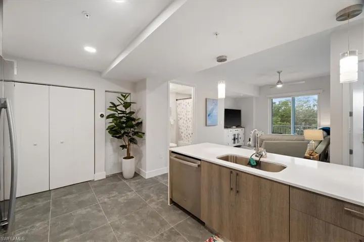 Kitchen featuring a sink, light countertops, dishwasher, and decorative light fixtures